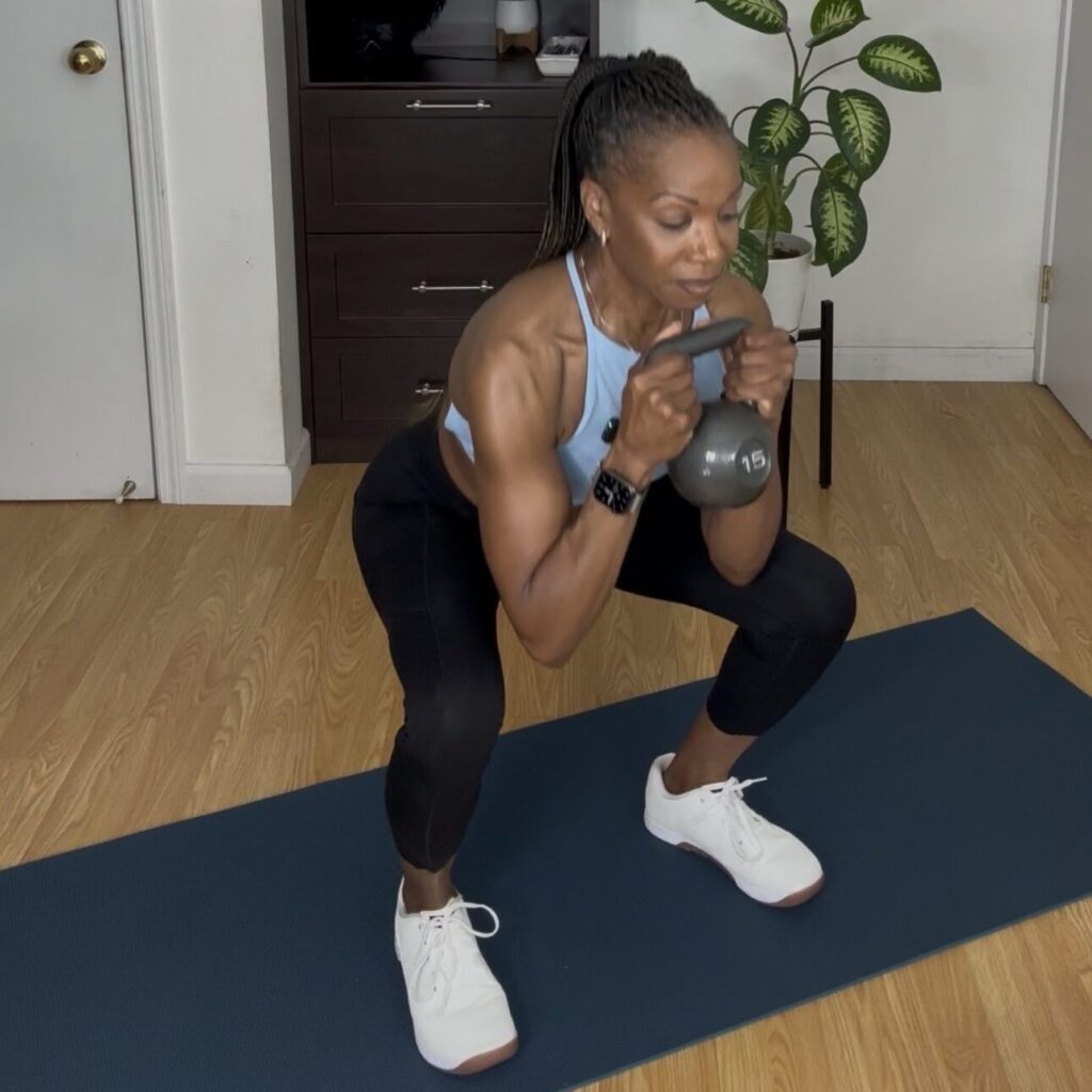 Tracie VanHook performing a kettlebell squat during an at-home strength workout.